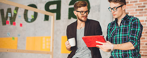 Zwei junge Männer schauen auf ein Tablet. Zwei junge Männer schauen auf ein Tablet.