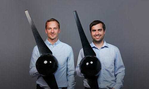 Dr.-Ing. Till Naumann und Andreas Amberger, zwei Männer mit Teilen ihrer Mikroturbine in den Händen, lächeln in die Kamera.