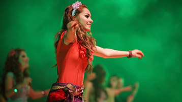 Eine Frau tanzt auf einer Bühne mit anderen Tänzerinnen.