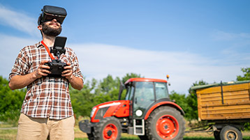 Ein Mann mit Virtual Reality Brille steht vor einem Traktor.