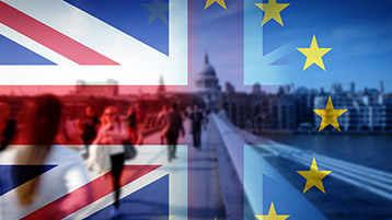 Die britische Nationalflagge und die Europaflagge im Verlauf, im Hintergrund gehen Menschen über eine Brücke.