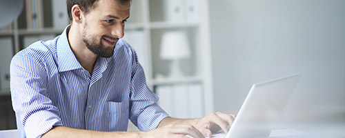 Mann arbeitet an weißem Laptop. Mann arbeitet an weißem Laptop.