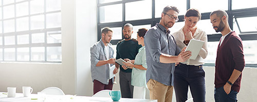 Menschen stehen in ein Gruppen in einem hellen Raum und schauen auf Tablets. Menschen stehen in ein Gruppen in einem hellen Raum und schauen auf Tablets.