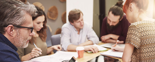 Männer und Frauen arbeiten gemeinsam an einem Tisch. Männer und Frauen arbeiten gemeinsam an einem Tisch.