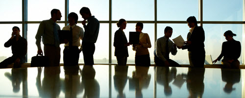 Arbeitende Hände zweier Personen an einem Schreibtisch mit Tassen, Stiften, Zetteln und einem Laptop. Arbeitende Hände zweier Personen an einem Schreibtisch mit Tassen, Stiften, Zetteln und einem Laptop.