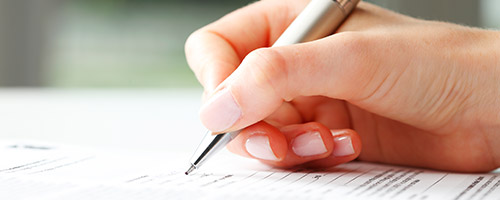 Eine Frauenhand schreibt mit einem Stift. Eine Frauenhand schreibt mit einem Stift.