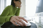 Frau sitzt am Computer mit Computermaus in der Hand