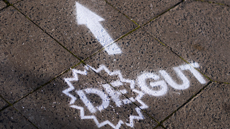 Weißer Pfeil und Schriftzug DEGUT auf grauem Pflaster Weißer Pfeil und Schriftzug DEGUT auf grauem Pflaster