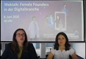 Standbild aus Video zeigt zwei Frau, die vor einer Kamera sitzen und eine Online-Diskussion führen, hinter ihnen ein großer Bildschirm